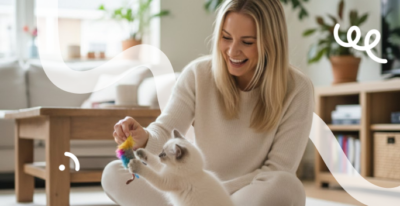 Blonde vrouw zit op de grond te spelen met een witte Ragdoll kitten