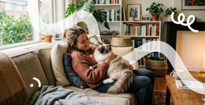 Een vrouw zit in haar woonkamer op de bank te knuffelen met haar Ragdoll kat