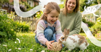 Een moeder zit met haar dochter in de tuin in het gras te spelen met hun konijn